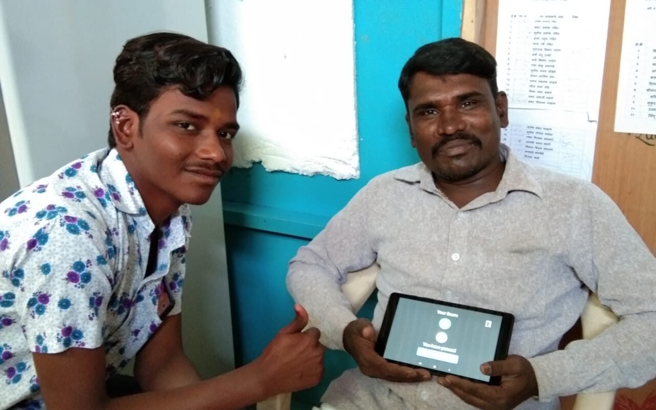 Two men, one showing a thumbs up, the other holding a digital tablet
